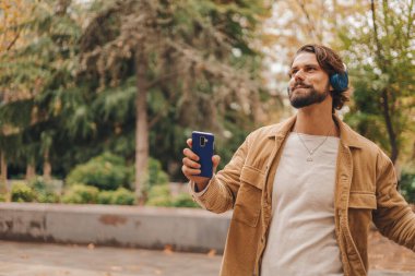 Parkta müzik dinleyen beyaz bir adamı yakından izleyin. Yüksek kalite fotoğraf.