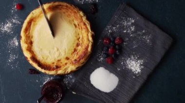 Basque cheesecake with strawberry jam, blueberries and raspberries, copy space, overhead view. Cutting a slice