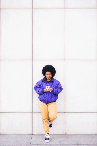 Joven Latina Afro Mujer Pie Pared Blanca Usando Teléfono Sonriendo — Foto de Stock