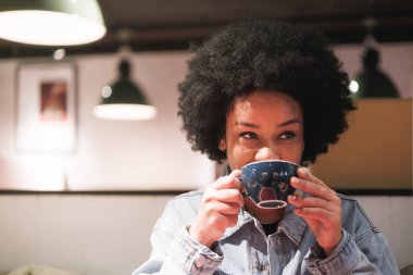 Elinde kahve tutan afro bir kadın, büyük bir gülümseme, yakın plan bir portre. Yüksek kalite fotoğraf