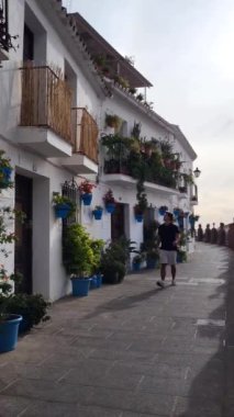 Genç turist tipik İspanyol beyaz kasabasını ziyaret ediyor. Sokak bitkiler ve flowepotlarla süslenmiş. Ağır çekim. Yüksek kaliteli FullHD görüntüler