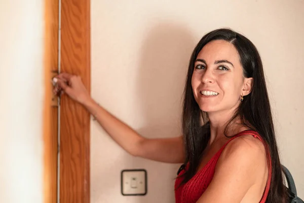 Smiling woman closing home door and leaving home, close up view. High quality photo