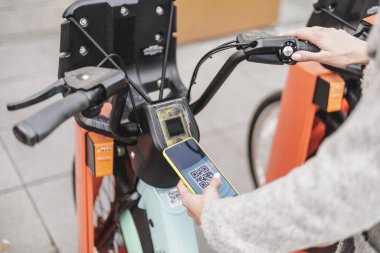 Woman unlocking electric bike with her phone. QR code. Eco-transportation concept. High quality photo