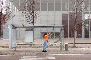 Turuncu elbiseli trans kadın otobüsü arıyor. Tam görüş. Yüksek kalite fotoğraf