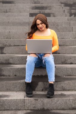Üniversite merdivenlerinde dizüstü bilgisayar kullanan transseksüel kadın öğrenci. Yüksek kalite fotoğraf