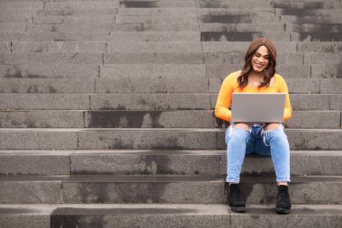 Üniversite merdivenlerinde dizüstü bilgisayar kullanan transseksüel kadın öğrenci. Merdiven boşluğunu kopyala. Yüksek kalite fotoğraf