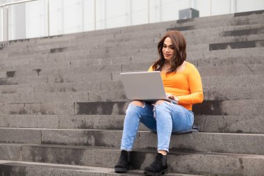 Üniversite merdivenlerinde dizüstü bilgisayar kullanan transseksüel kadın öğrenci. Yüksek kalite fotoğraf
