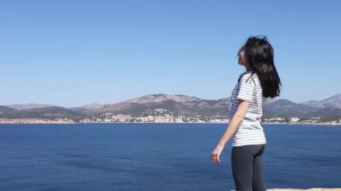 Genç kadın Akdeniz 'i düşünüyor güneşli günün ve temiz havanın tadını çıkarıyor. Yüksek kaliteli FullHD görüntüler