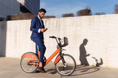 Ofise bisikletle gidip cep telefonu kullanan gülümseyen bir işadamı. Yüksek kalite fotoğraf