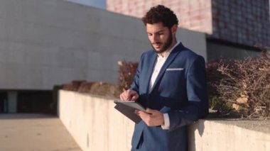 Finans bölgesinde dijital tablet kullanan yakışıklı İspanyol işadamı. Yüksek kaliteli FullHD görüntüler