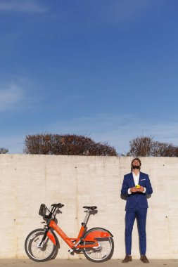 İş adamı gökyüzüne bakıyor. Bisiklet duvara yaslanıyor. Gökyüzü arkaplan kopyalama alanı Yüksek kalite fotoğraf