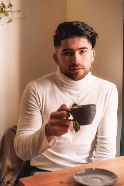 Portrait of handsome colombian male with a cup of coffee looking to the camera. High quality photo