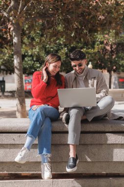 Parkta dizüstü bilgisayar kullanan iki mutlu öğrenci. Dikey çekim. Yüksek kalite fotoğraf