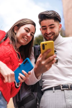 İki Z gen arkadaşı cep telefonu kullanıyor ve sokakta gülümsüyor. Yüksek kalite fotoğraf