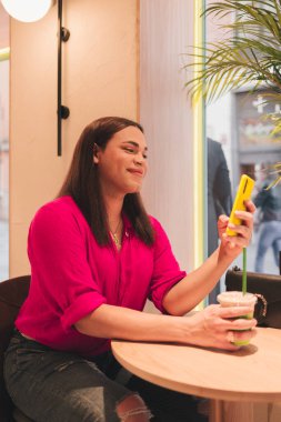 Trans kadın kibrit çay içiyor ve cep telefonu kullanıyor. LGBT konsepti. Yüksek kalite fotoğraf