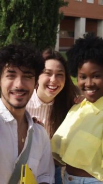 Üniversite kampüsündeki uluslararası öğrenciler sosyal medya için akıllı telefonlarıyla selfie çekiyorlar. Yüksek kaliteli FullHD görüntüler