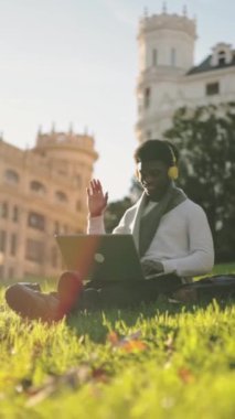 Üniversite kampüsünde müzik dinlerken dizüstü bilgisayar kullanan Afrikalı Amerikalı bir öğrenci. Üniversite yaşam tarzı. Yüksek kalite fotoğraf