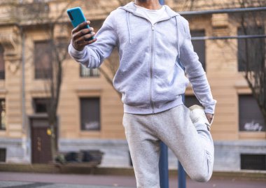 Tanımlanamayan Afro-Amerikan erkek, bacaklarını esnetiyor ve cep telefonu kullanıyor. Yüksek kalite fotoğraf