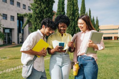 Üniversite arkadaşları kampüste akıllı telefon kullanıyor. Etnik çeşitlilik, uluslararası üniversite. Yüksek kalite fotoğraf