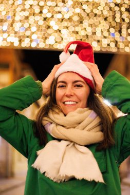 Cheerful and cute latin woman with christmas hat smiling to the camera on Christmas Eve. High quality photo clipart