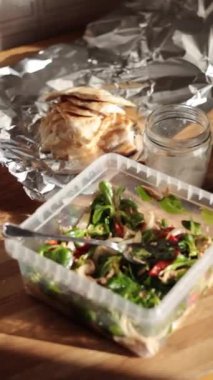 Tepsi takımında sağlıklı salata ve ahşap bir masada tavuk slaytları. Ev yapımı paket yemek. Yüksek kaliteli FullHD görüntüler
