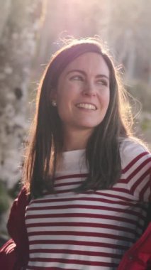 Günbatımında yürüyüş yaptıktan sonra ormanda kameraya gülümseyen güzel İspanyol kadın. Ilık arka ışık. Yüksek kaliteli FullHD görüntüler