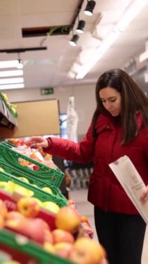 Kırmızı ceketli Latin kadın süpermarkette meyve seçiyor. Yüksek kaliteli FullHD görüntüler