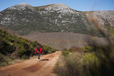 Kırmızı elbiseli bir kadın güzel bir manzarada yürüyüş yapıyor. Tam görüş, kopyalama alanı. Yüksek kalite fotoğraf