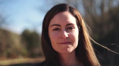 Kırsal kesimde kameraya gülümseyen sevimli genç bir kadın. Yakın plan portre. Yüksek kaliteli FullHD görüntüler