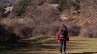 Kırmızı kışlık giysiler giyen genç bir kadının doğa yürüyüşü yapışının arkası. Yüksek kaliteli FullHD görüntüler