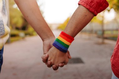 Şehirde yürürken gökkuşağı bilekliğini gösteren Latin lgbt çifti