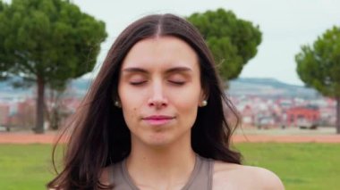 Gözleri kapalı bir kadın parkta huzuru bulur. Egzersize başlamadan önce derin bir nefes alıyor.