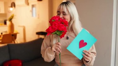 Sevgililer günü kartı ve kırmızı güller gösteren güzel genç bir kadın.