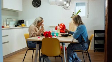 Romantik sevgililer günü yemeğinin keyfini çıkaran iki kadın modern mutfaklarında birlikte yemek yiyorlar.