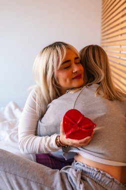 İki kadın sevgililer gününde birbirlerine sarılıyor, hediyelerini veriyor ve birbirlerine şefkat gösteriyorlar.