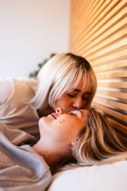 Sevgililer Günü sabahı yatakta sevgilisini nazikçe öpen bir kadın.