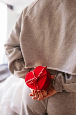 Sevgililer günü için kalp şeklinde hediye kutusuyla ortağına sürpriz yapan bir kadın.