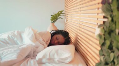 Genç bir kadın rahat yatağında rahat bir uyku çekiyor. Ev ortamının huzurunu kucaklıyor.