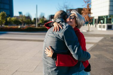 Üst düzey arkadaşlar şehir ortamında sıcak bir kucaklaşmayı paylaşırlar.