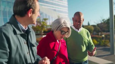 Üç yetişkin arkadaş dışarıda yürürken sohbet etmekten zevk alır.