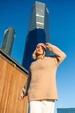 Şık sarışın model kentsel gökdelen arka planına eğiliyor