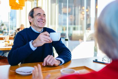 Modern restorandaki kahve toplantısı sırasında neşeli olgun yöneticiler sohbet ediyorlar.