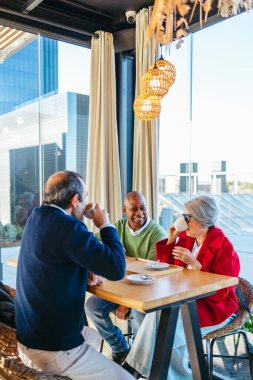 Olgun arkadaşlar sosyalleşiyorlar, rahat bir kafede kahve içiyorlar.