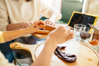 Anne ve kızı çikolatalı kurabiyeler için hamur hazırlıyorlar, ahşap bir oklava kullanıyorlar, tabletten online tarifi takip ediyorlar.