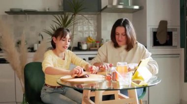 Anne ve kızı tabletten online tarifi takip ederek kurabiye hazırlıyorlar.