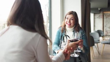 Alışveriş gezisinden sonra kafede kırmızı şarap içip sohbet eden iki kadın arkadaşlığı ve boş vakitleri kutluyorlar.