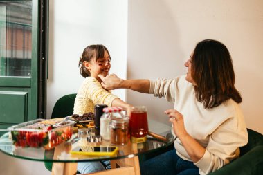 Annem eğlenceli bir yemek oturumunda kızının yanağına çikolata sürüyor..