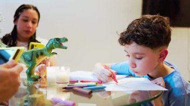 Latin çocuk evde pastel boyalarla resim çiziyor, konsantre çocuk yaratıcı aktivitelerden zevk alıyor.