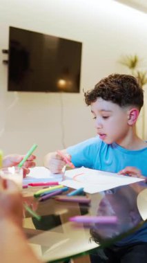 Latin çocuk evde pastel boyalarla resim çiziyor, konsantre çocuk yaratıcı aktivitelerden zevk alıyor.