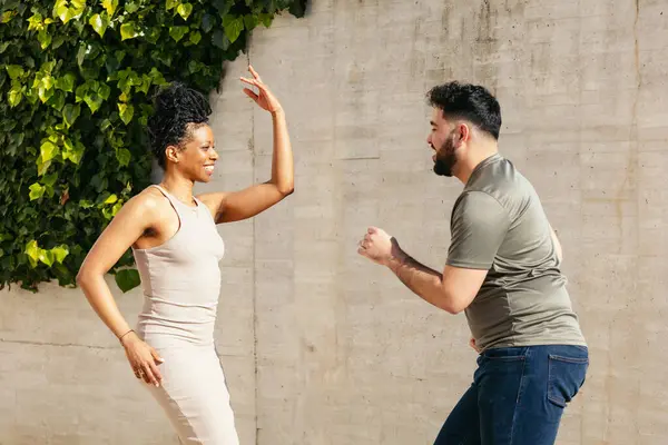 Kadın ve erkek, çimento duvarın yanında salsa yapıyor.